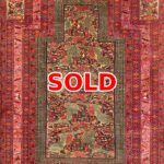 Persian-style decorative rug with red borders and a floral central pattern; marked SOLD.