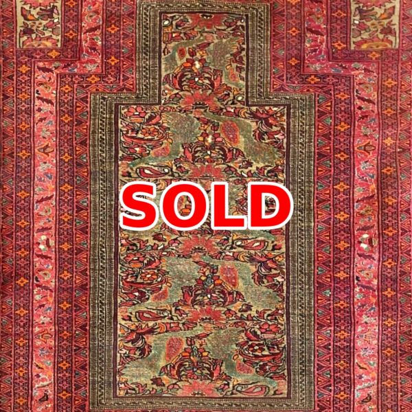 Persian-style decorative rug with red borders and a floral central pattern; marked SOLD.